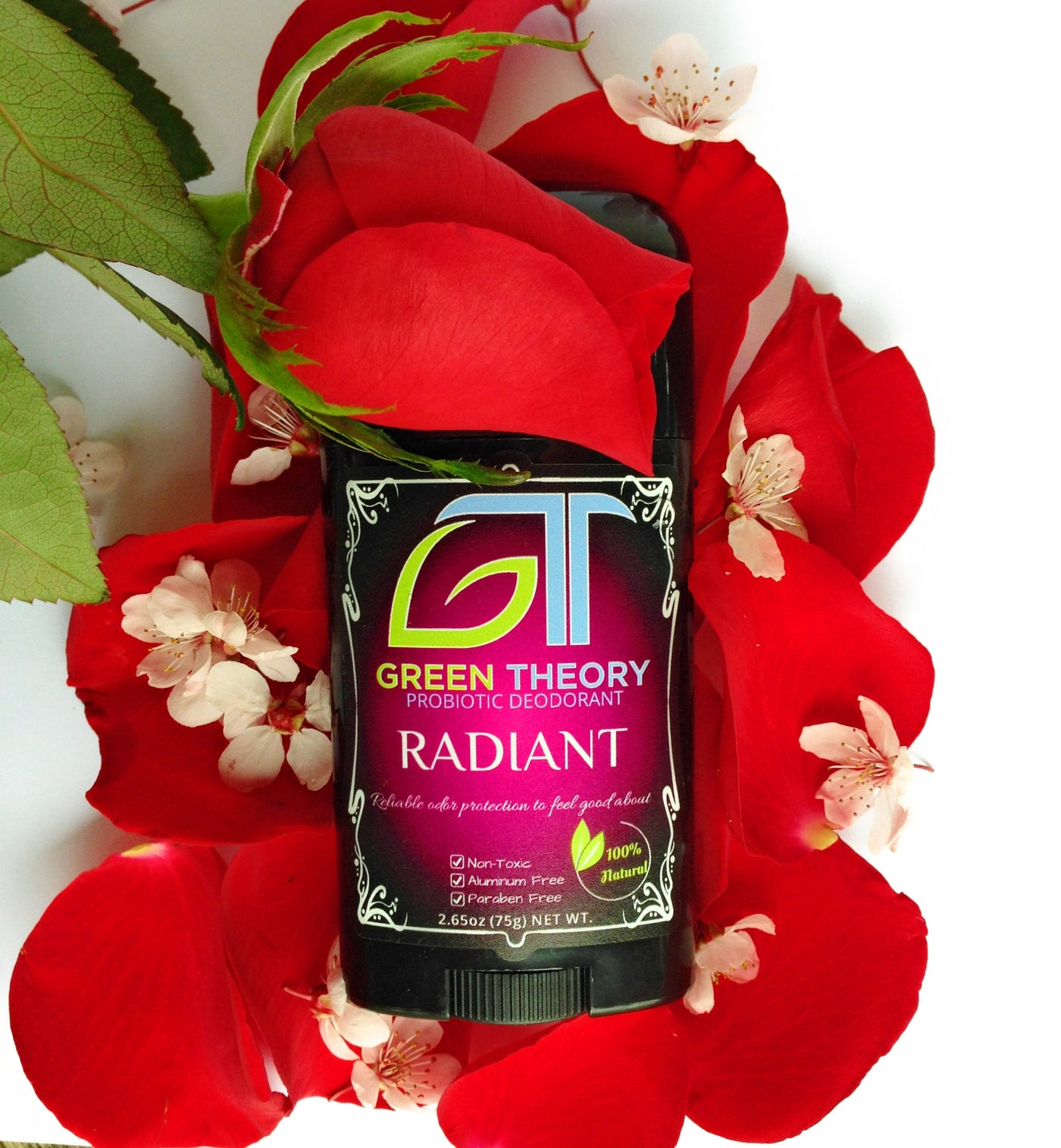 Photo of Green Theory Radiant aluminum free probiotic deodorant for women laying on top of a white background covered with beautiful rose petals. A rose is placed over the cap of the deodorant