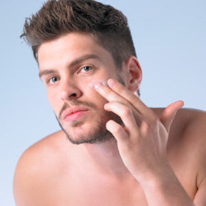 man touching his face and applying cream