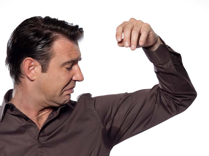 disgusted man looking at a sweat stain in his armpit