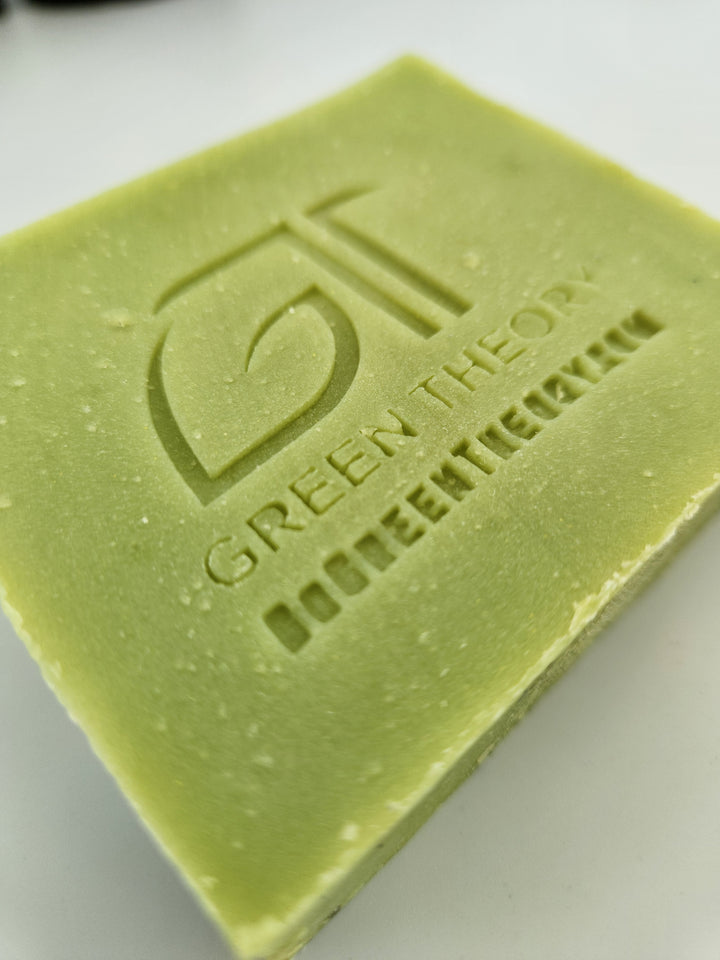 Close up photo of green theory taurus all natural soap. Bar is laying down with its face side up and turned at an angle. soap bar is lime green with the green theory logo and website stamped into the bar