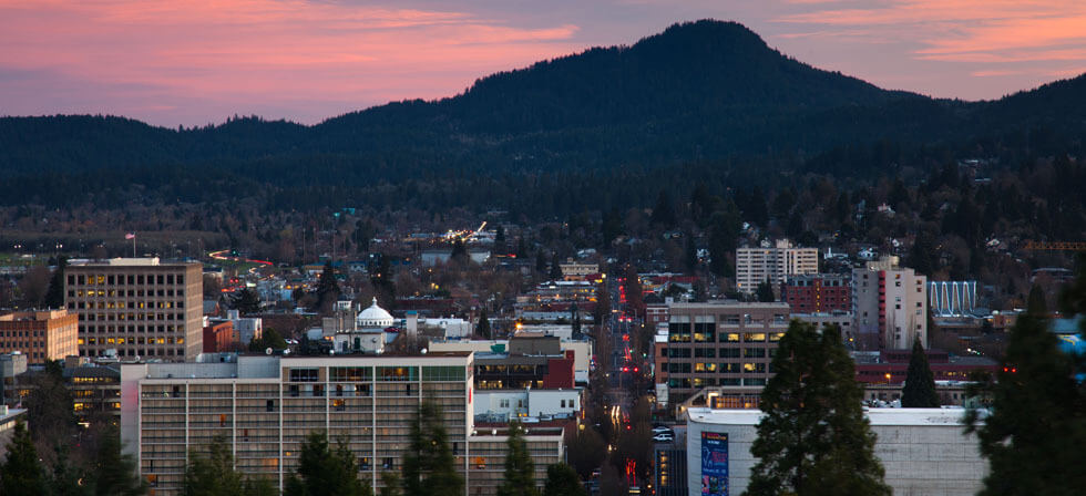 picture of Eugene oregon skyline facing spencer butter at sunset. Text says proudly made in Eugene, Oregon