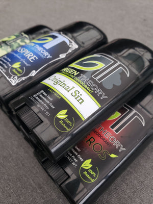 stack of green theory all natural probiotic deodorants. Pictured are original sin mens deodorant, inspire womens deodorant and anteros mens deodorant on a grey background. Deodorant sticks are a sleek black plastic container with large GT logo and scent