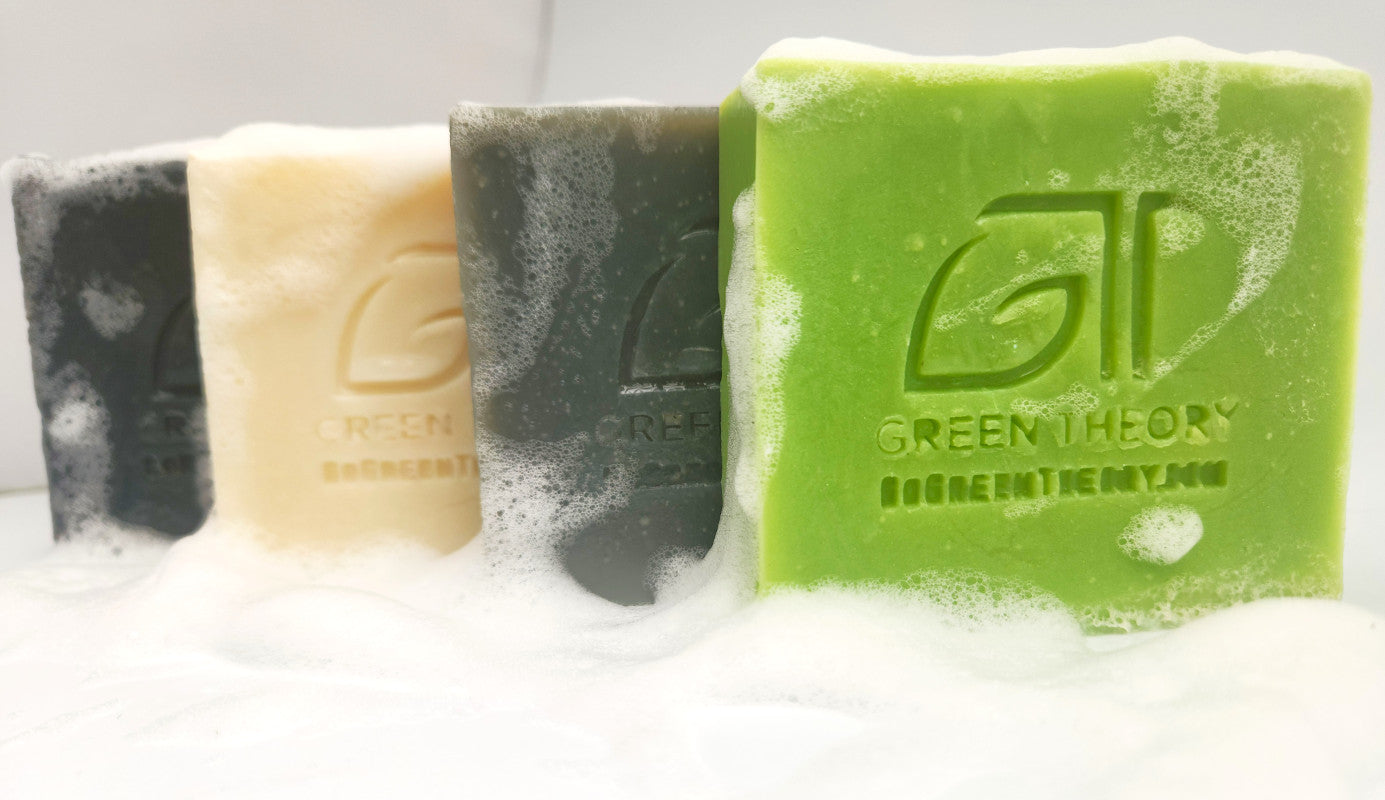 Photograph of Green Theory natural soap and shampoo bars horizontally lined up covered in suds