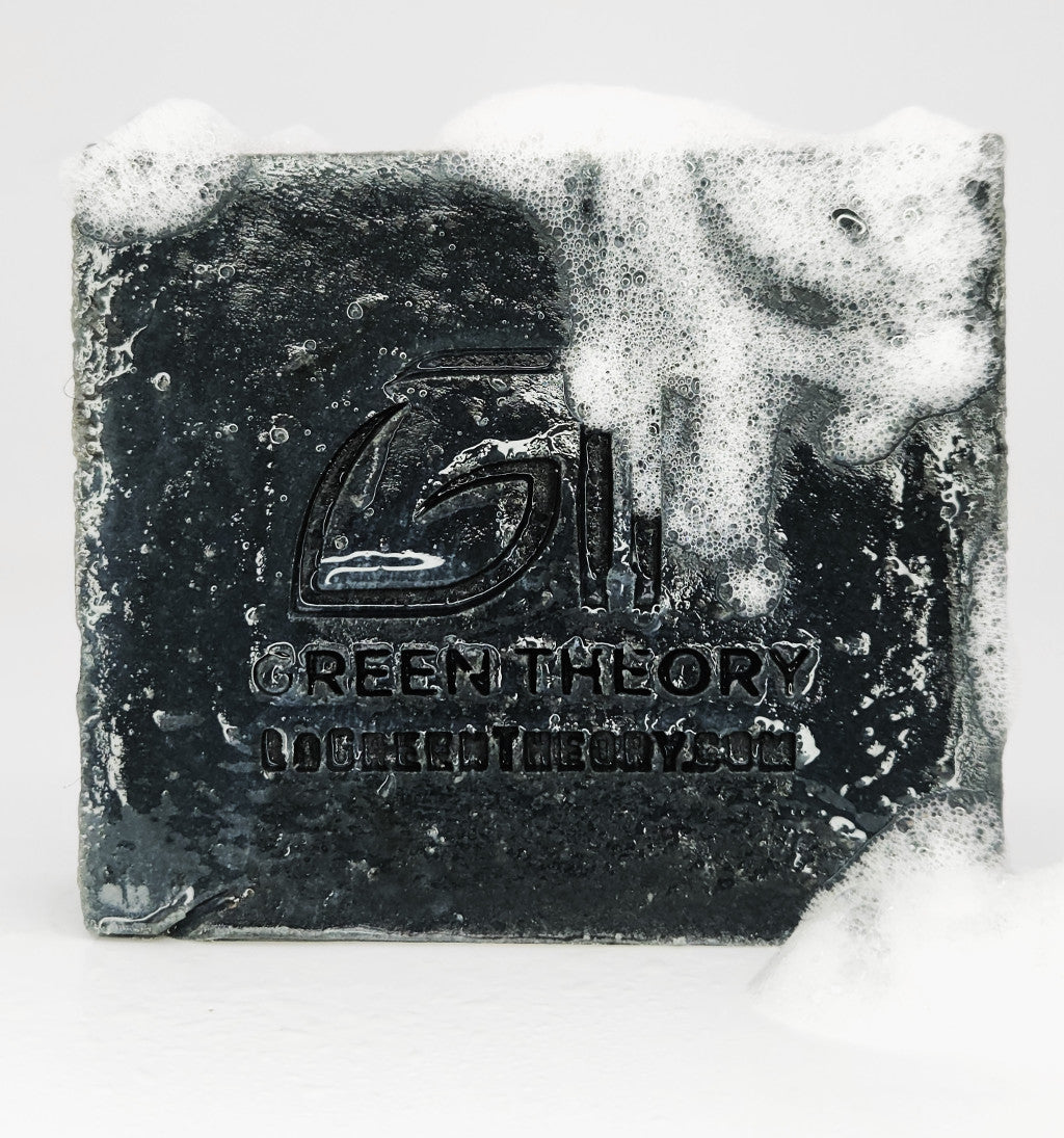 photo of Green Theory's Phoenix soap bar thats black and has the Green Theory logo impressed into the bar. The soap is wet and the top is covered in suds