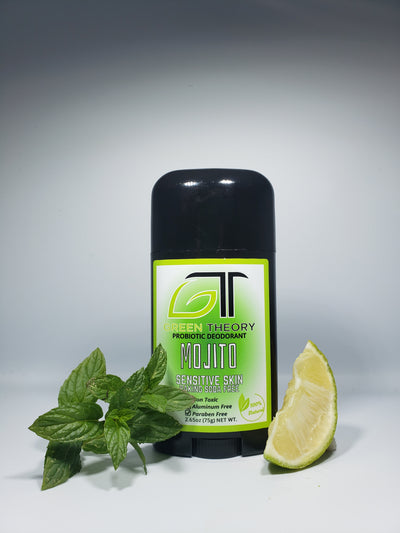 photo of green theory Mojito baking soda free, probiotic natural aluminum free deodorant. Stick is standing in front of a shadowy white background with mint leaves to the left and and lime wedge to the right.