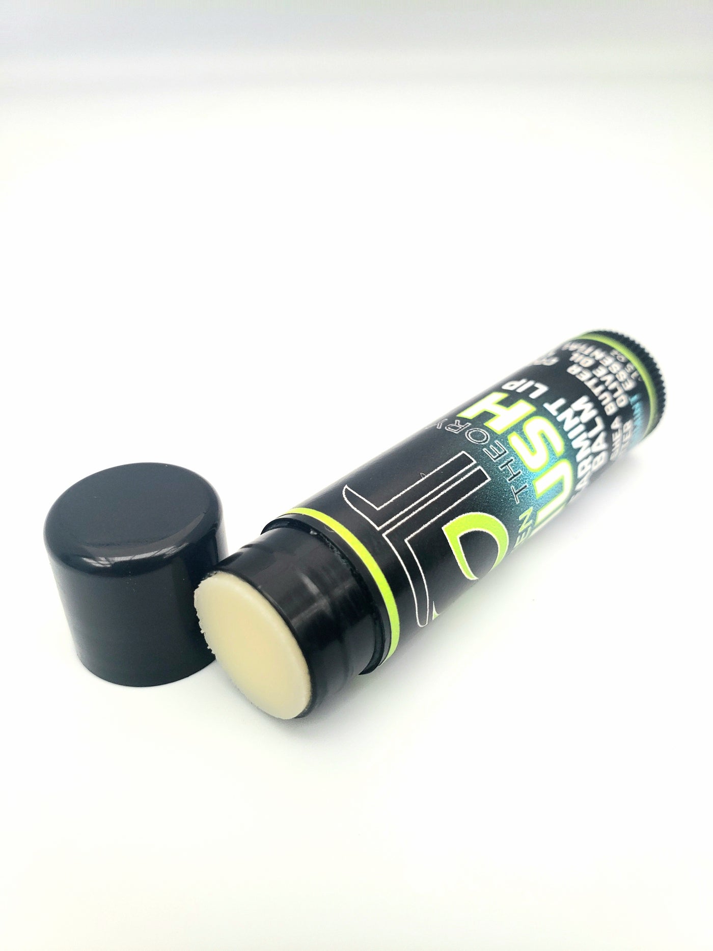 photo of green theory hush all natural spearmint lip balm laying on its side with the cap off to show product texture.