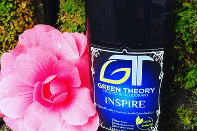 photo of Green Theory Inspire probiotic aluminum free natural deodorant for women against a mossy background next to a very vibrant, oversaturated pink flower blossom